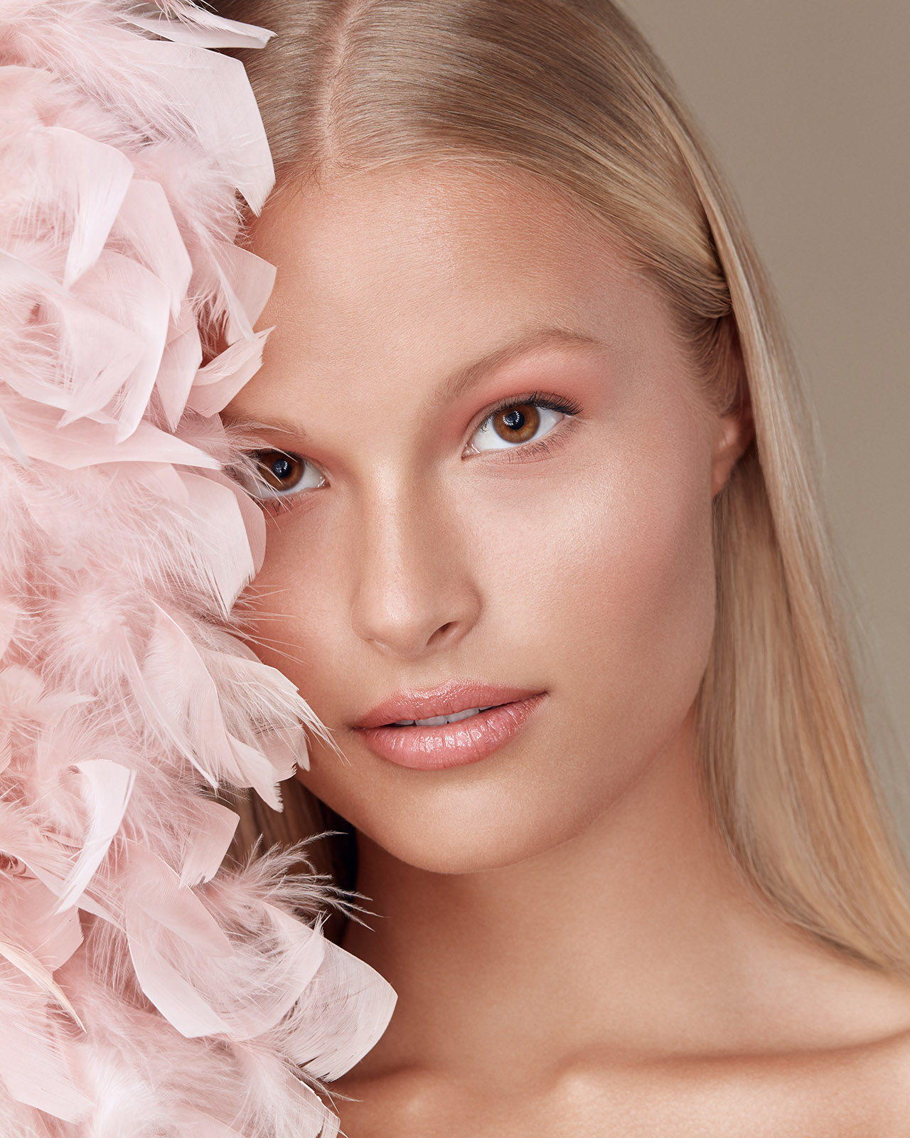 Beauty photography of blonde woman with pink feathers
